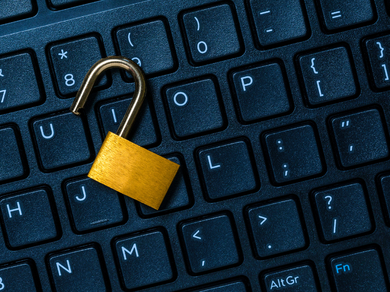 Unlocked brass padlock resting on a black computer keyboard.