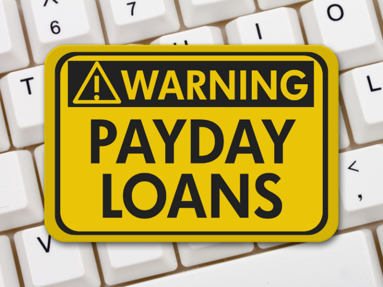 Yellow and black warning sign reading "Warning Payday Loans" on white computer keyboard.