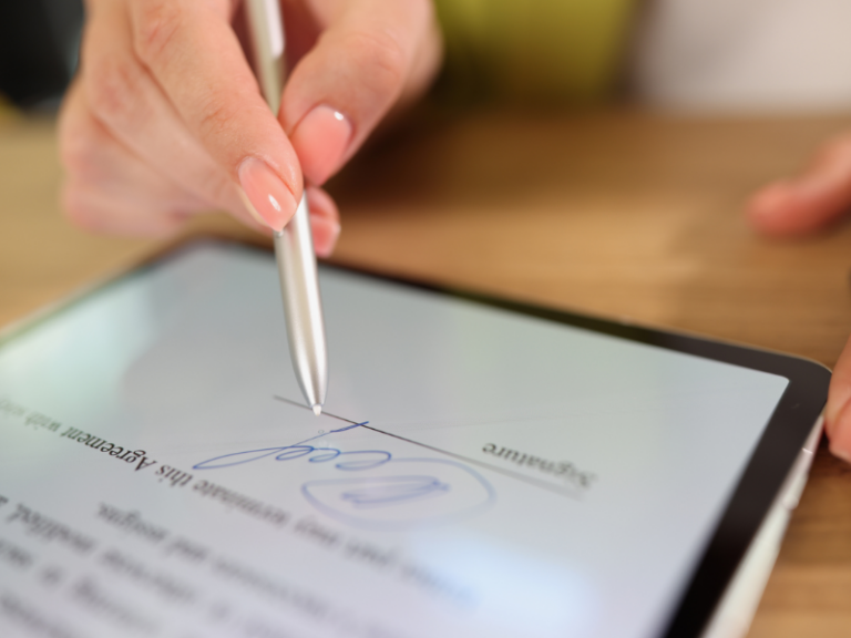 Close-up of a hand using a stylus to sign a digital document on a tablet screen.