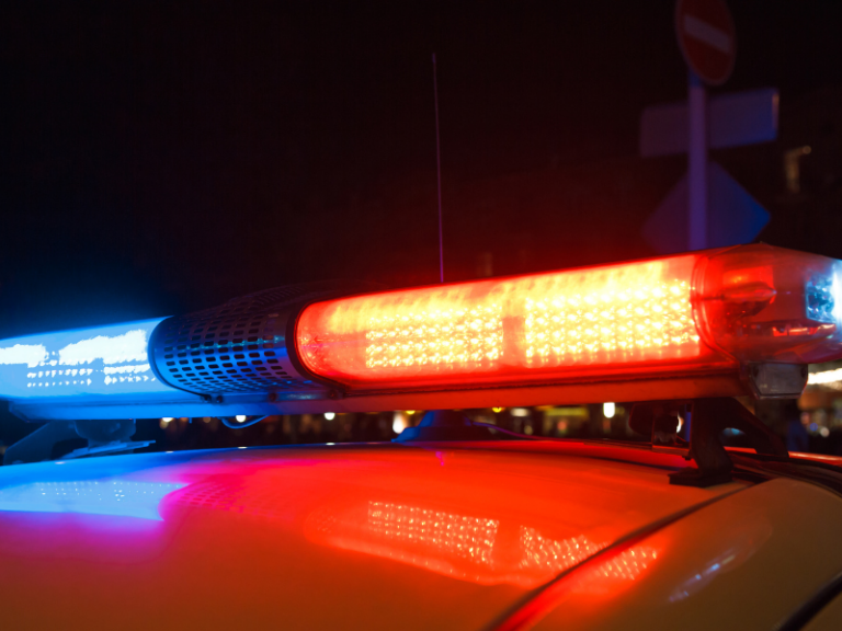 Close-up of red and blue police car emergency lights illuminated at night.