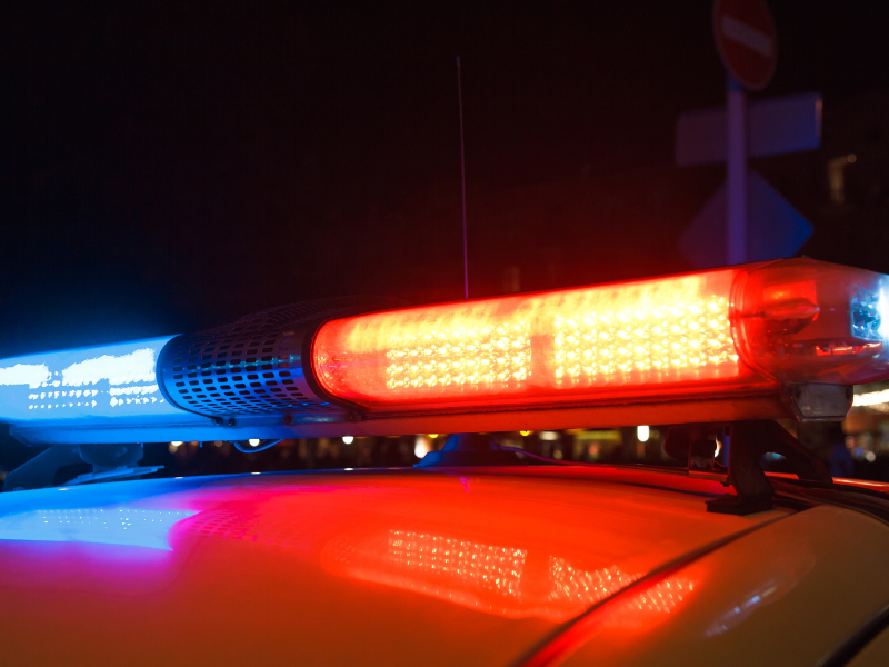Close-up of red and blue police car emergency lights illuminated at night.