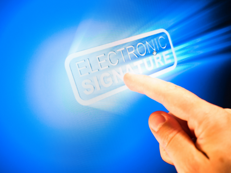 Close-up of a hand pointing to a glowing "Electronic Signature" icon on a blue digital screen.
