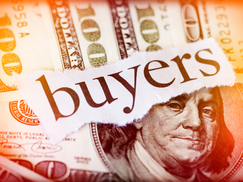 Close-up of a torn paper with the word "buyers" placed on hundred-dollar bills.