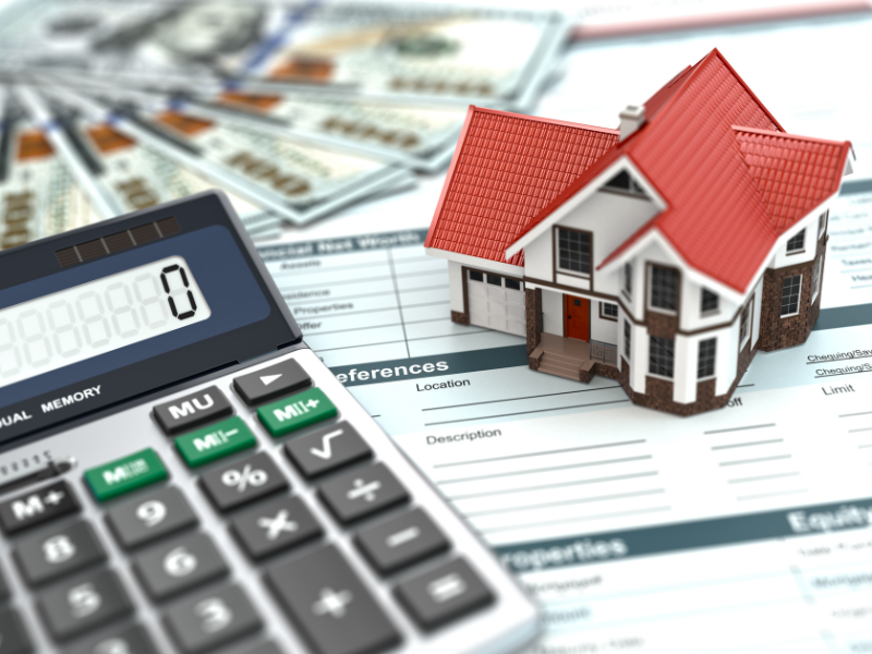 Calculator, model house with red roof, US dollar bills, and financial documents.