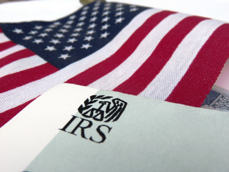 Close-up of an IRS document partially covering an American flag with red, white, and blue colors.