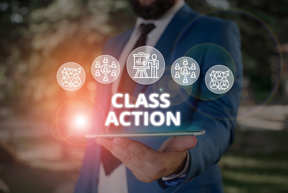 Business professional holding tablet with floating icons and glowing text "Class Action