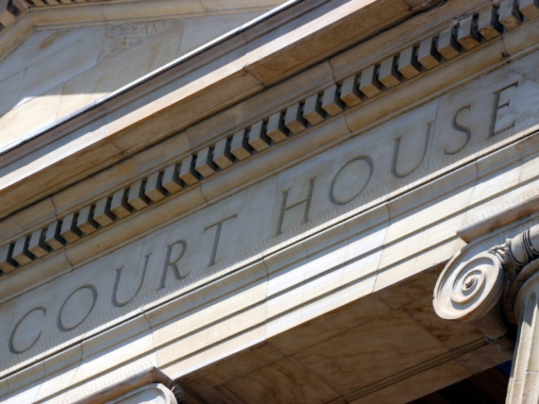 Close-up of beige stone courthouse facade with engraved "COURT HOUSE" text and architectural molding.