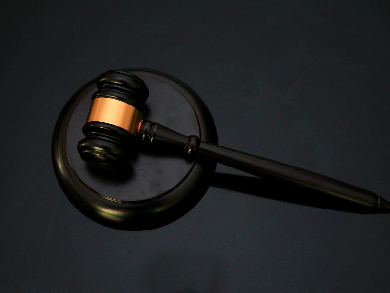 Dark wooden judge's gavel with a gold band resting on a matching sound block.