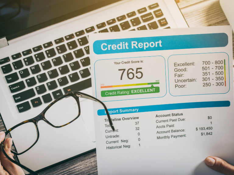 Credit report showing a credit score of 765 with an excellent rating, held above a laptop keyboard.