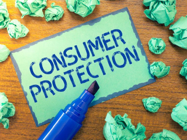 Green card with blue text "Consumer Protection" surrounded by crumpled green paper balls and a blue marker.