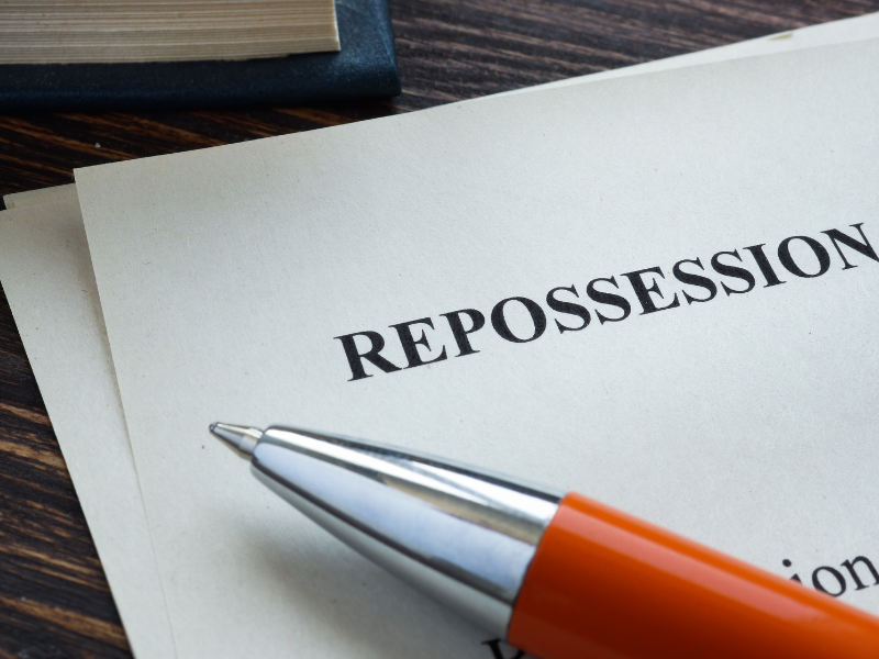 Close-up of a document titled "REPOSSESSION" with a silver and orange pen resting on it.
