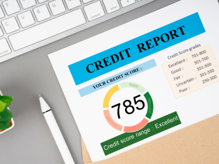 Credit report showing a score of 785 labeled as excellent, with a keyboard and pen nearby.
