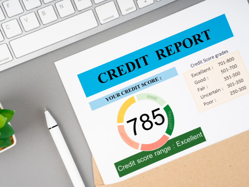 Credit report showing a score of 785 labeled as excellent, with a keyboard and pen nearby.