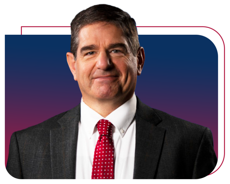 Portrait of a middle-aged man in a dark suit, white shirt, and red patterned tie against a blue and purple gradient background.