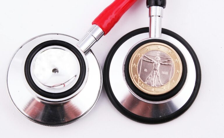 Close-up of a stethoscope with red tubing and a Euro coin placed on the chest piece.