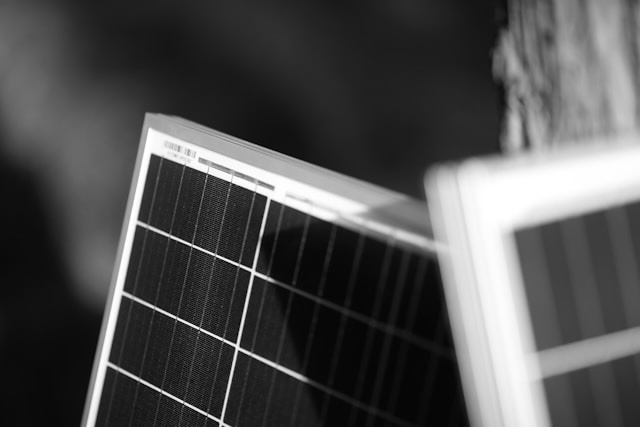 Close-up black and white image of solar panels with grid patterns and blurred background.