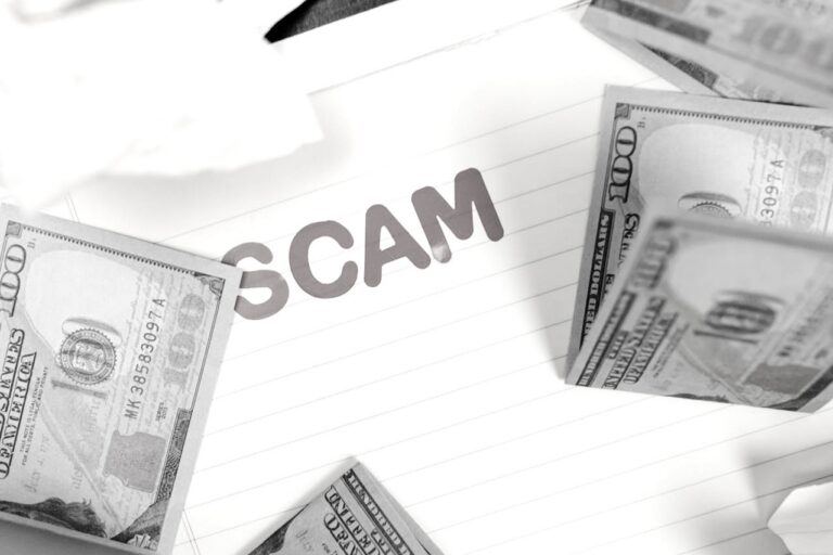 Notepad with the word "SCAM" surrounded by multiple US hundred-dollar bills.