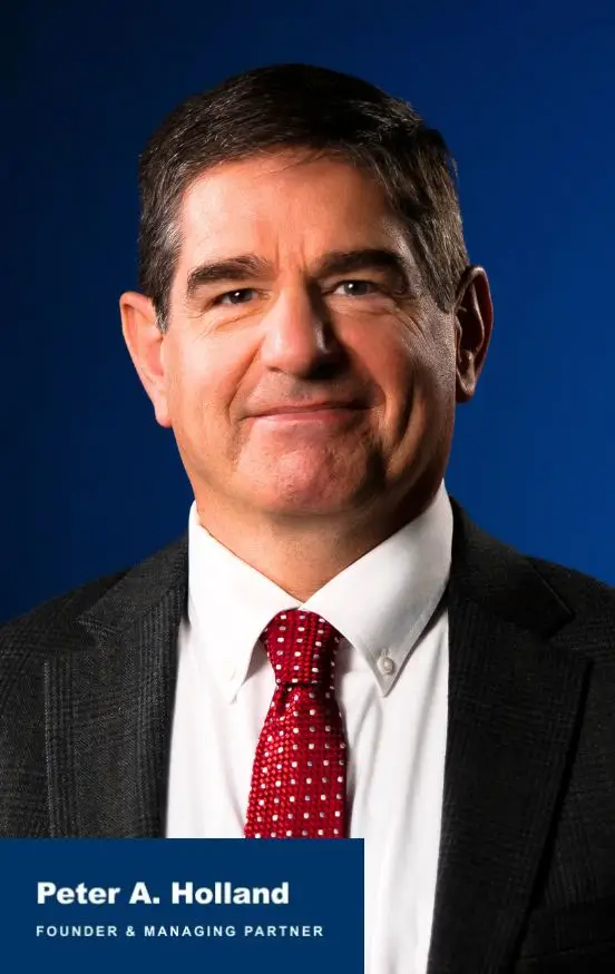 Professional headshot of a man in a dark suit, white shirt, and red patterned tie against a blue background.