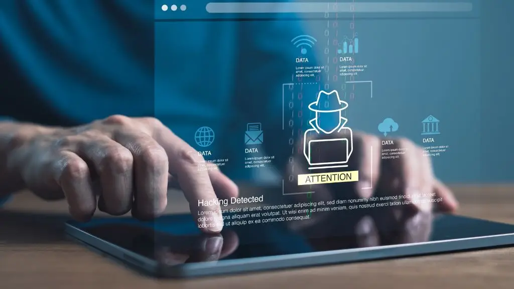 Close-up of hands interacting with a tablet displaying digital hacking detection and data icons.