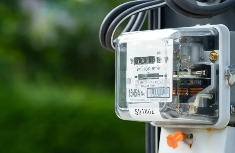 Close-up of a transparent watt-hour electric meter mounted outdoors with visible numeric display and wiring.